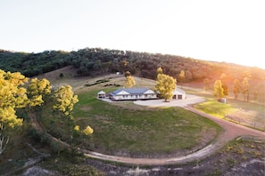 Situated on a gently sloping hill, this single-story residence offers a secluded retreat amidst a well-maintained lawn and trees.