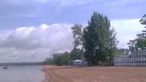 A sandy beach with tire tracks and a boat in the water.