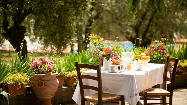 An outdoor dining area with a table set for two, surrounded by potted plants and flowers. - Nice apartment for 6 guests with WIFI, pool, close to Florence (Romola)