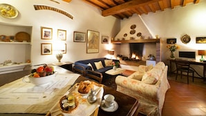 A cozy living room with a fireplace, wooden beams, a sofa, a dining table with food, and various decorative items. - Nice apartment for 6 guests with WIFI, pool, close to Florence (Romola)