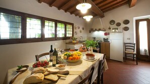 A dining area with a table set for a meal, a kitchen in the background, and a rustic wooden ceiling. - Nice apartment for 6 guests with WIFI, pool, close to Florence (Romola)