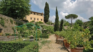 A garden pathway with potted plants and a pergola structure. - Nice apartment for 6 guests with WIFI, pool, close to Florence (Romola)