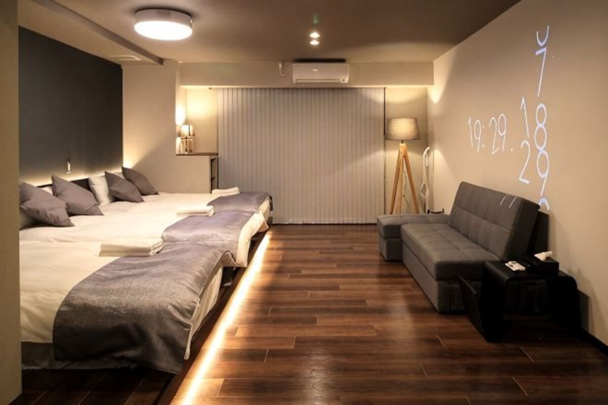 A hotel room with a bed, sofa, and a wall with a projection.