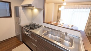 Una cocina moderna con electrodomésticos de acero inoxidable, un lavamanos grande y un ventanal con cortinas.
