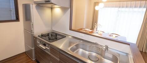 Una cocina moderna con electrodomésticos de acero inoxidable, un lavamanos grande y un ventanal con cortinas.