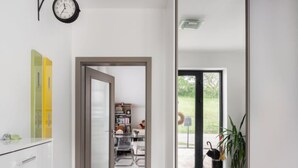 Un pasillo moderno con una puerta que da a una habitación con una estantería y vistas al exterior.