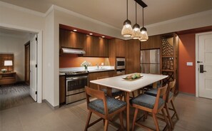 Una cocina moderna con armarios de madera, encimera blanca y comedor con cuatro sillas.