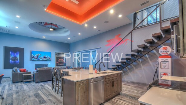 Moderni keittiö, jossa on keskeinen saareke, integroidut kodinkoneet ja portaikko, joka johtaa ylemmälle tasolle.