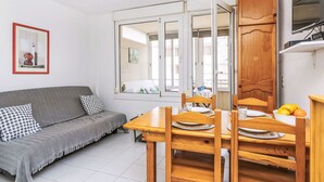 Ein kompakter Wohnbereich mit Sofa, Esstisch, Stühlen und einer Küchenzeile.