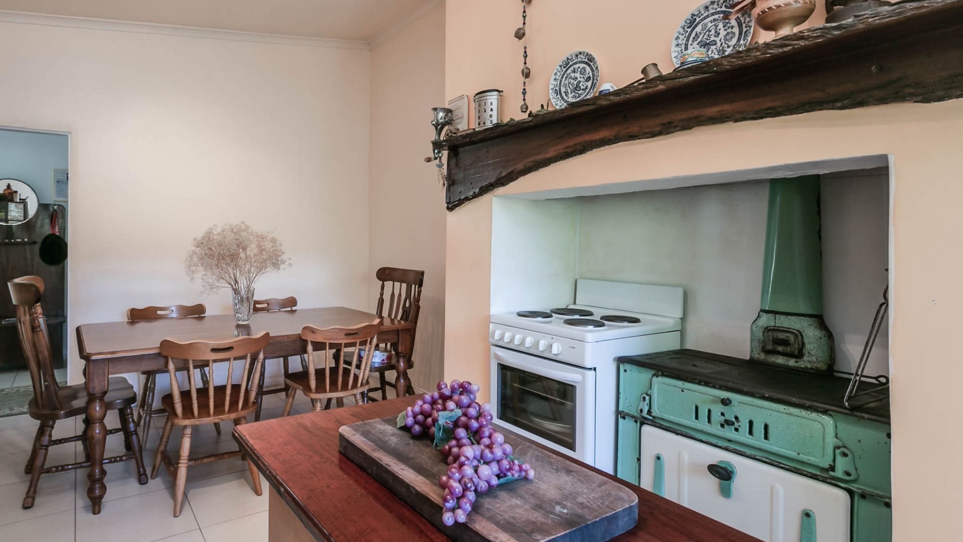 A kitchen with a white stove, a green oven, and a wooden dining table with chairs.