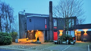 Un bâtiment moderne avec une façade en briques, une porte rouge et une cheminée.
