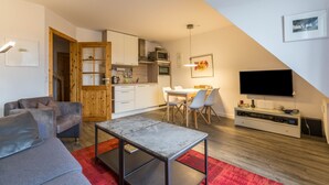 Un espace de vie compact comprenant une kitchenette, un coin repas et un téléviseur à écran plat.