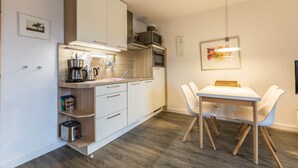 Une cuisine moderne avec des meubles blancs, un four à micro-ondes et un coin repas comprenant une table et des chaises.