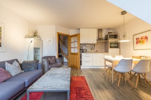 Un salon moderne avec un canapé, une table basse et un coin repas avec des chaises.