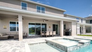 Una casa moderna con piscina, mobiliario exterior y un patio cubierto.