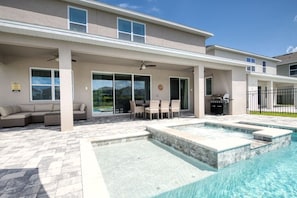 Une maison moderne dotée d’une piscine, d’un espace salon extérieur et d’un patio couvert.