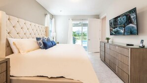 Un dormitorio con una cama grande, un televisor montado en la pared y vistas al exterior a través de una puerta corrediza.