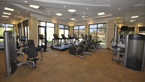 Et fitnesscenter med løbebånd, crosstrainere og styrkeudstyr.