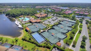 Ovenfra ses et resort med flere tennisbaner, en swimmingpool og en sø.