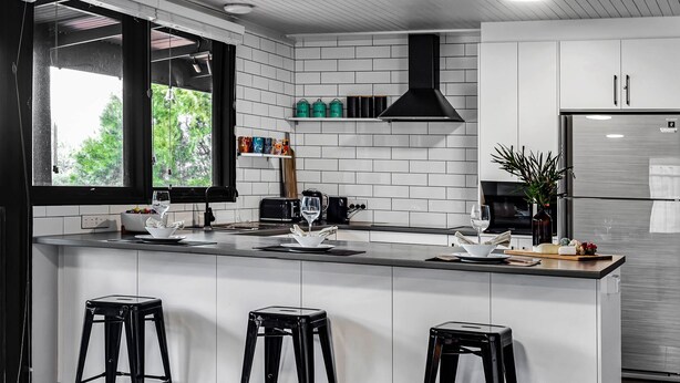 A modern kitchen with white subway tiles, a black hood, stainless steel appliances, and a large window. - Silvers Anchor - 2 Bennett Street (CARRICKALINGA)