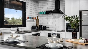 A modern kitchen with white subway tiles, a black range hood, and a large window overlooking greenery. - Silvers Anchor - 2 Bennett Street (CARRICKALINGA)