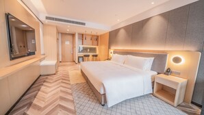 A modern hotel room with a large bed, a bedside table, a mirror, and a kitchenette area. - Holiday Inn Xi’an High Tech Zone by IHG (Xi'an)