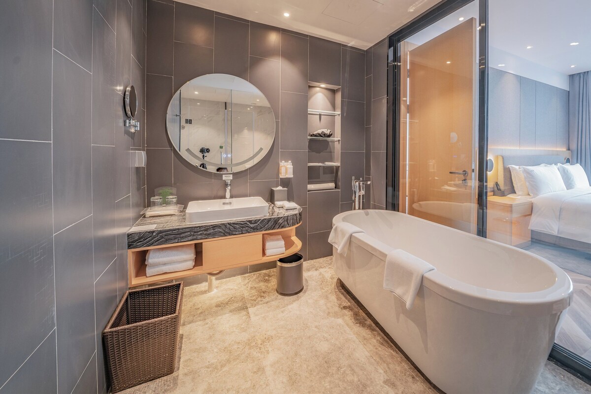 A modern bathroom with a freestanding bathtub, a large mirror, and a glass-enclosed shower area.