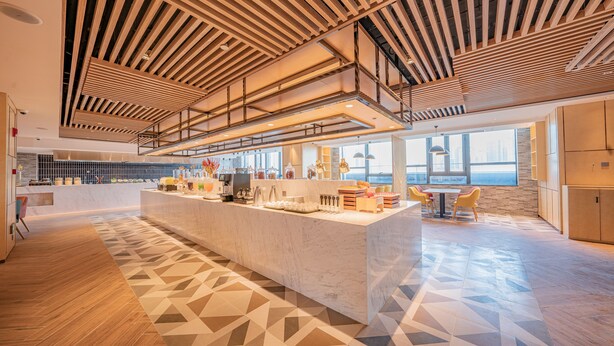 A modern kitchen with a central island, wooden ceiling beams, and large windows offering views of the city. - Holiday Inn Xi’an High Tech Zone by IHG (Xi'an)