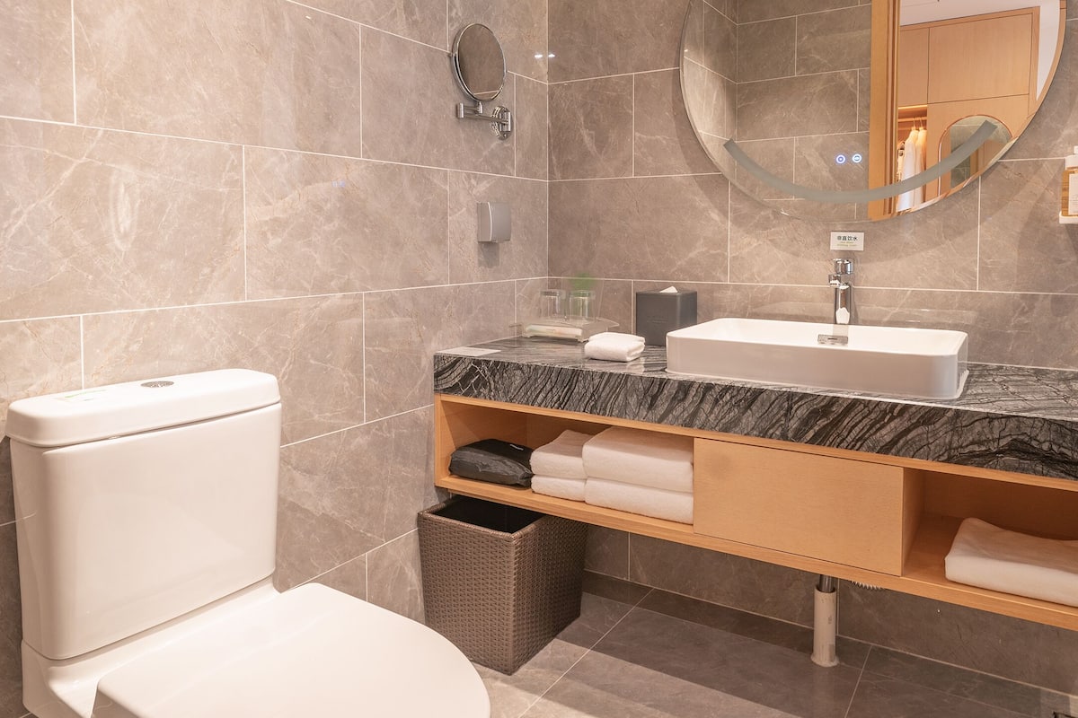 A modern bathroom with a toilet, sink, and mirror.