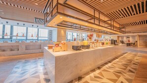 A modern hotel lobby with a marble reception desk, a coffee station, and a view of the city through large windows. - Holiday Inn Xi’an High Tech Zone by IHG (Xi'an)