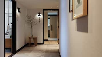 Un pasillo con piso de madera, una planta en maceta y una puerta que da a otra habitación.