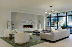 A modern living room with a fireplace, comfortable seating, and large windows.