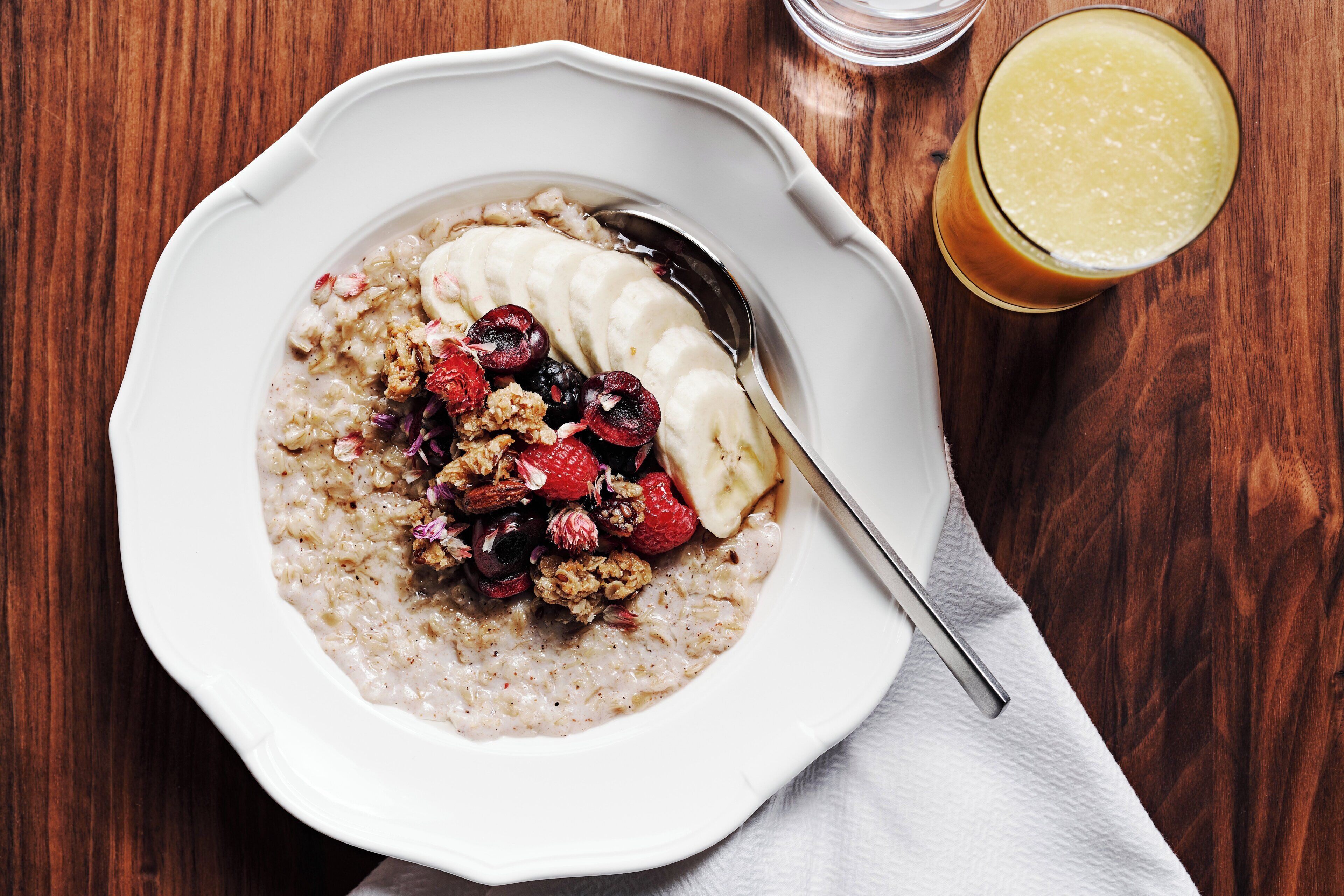 A bowl of oatmeal with fruits and nuts on a wooden table.