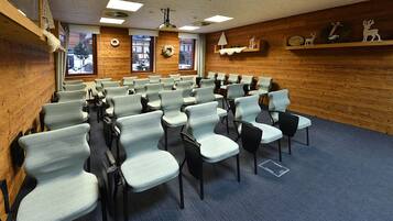 Un salón de conferencias con filas de sillas, paredes de madera y vistas al exterior.