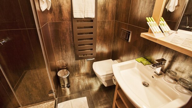 Un baño moderno con tocador de madera, inodoro, lavamanos y perchero.