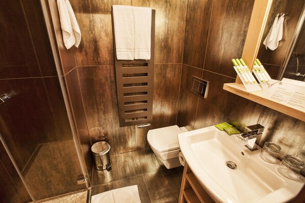 Un baño moderno con tocador de madera, inodoro, lavamanos y perchero.