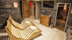 A spa room with a wooden bench, stone walls, a wooden dresser, and a television mounted on the wall. - Aplend Kukucka Mountain Hotel & Residences (Vysoké Tatry)