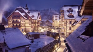 A traditional European village at night with snow-covered buildings and a lit street.