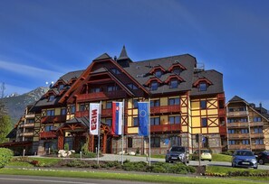 Un hotel de varios pisos con arquitectura alpina tradicional, con balcones y fachada de piedra.
