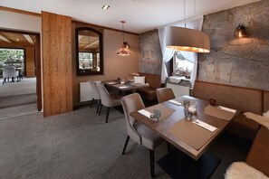 A modern dining area with a stone wall, wooden beams, and a large window. - Aplend Kukucka Mountain Hotel & Residences (Vysoké Tatry)