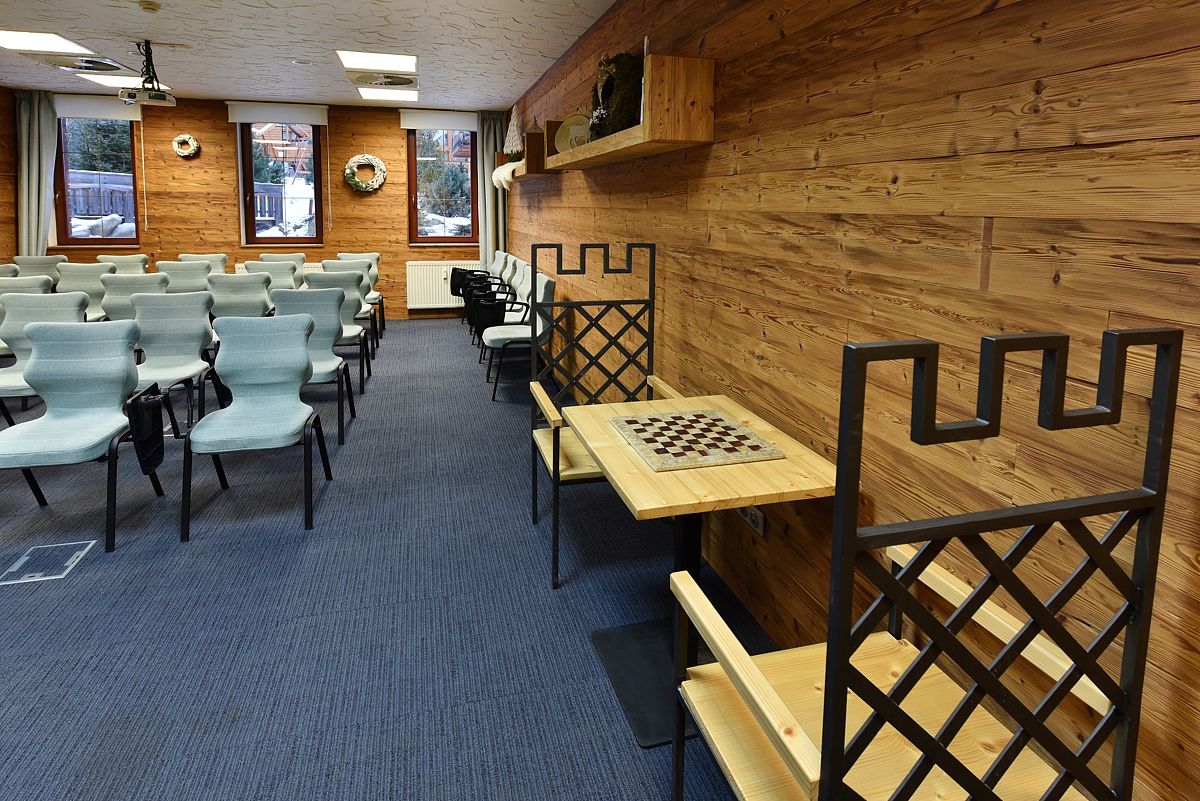 Un salón de conferencias con filas de sillas, una mesa de ajedrez y paredes de madera.