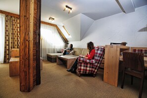 Una sala de estar acogedora con techo alto, vigas de madera, un sofá, una mesa de centro y una lámpara.