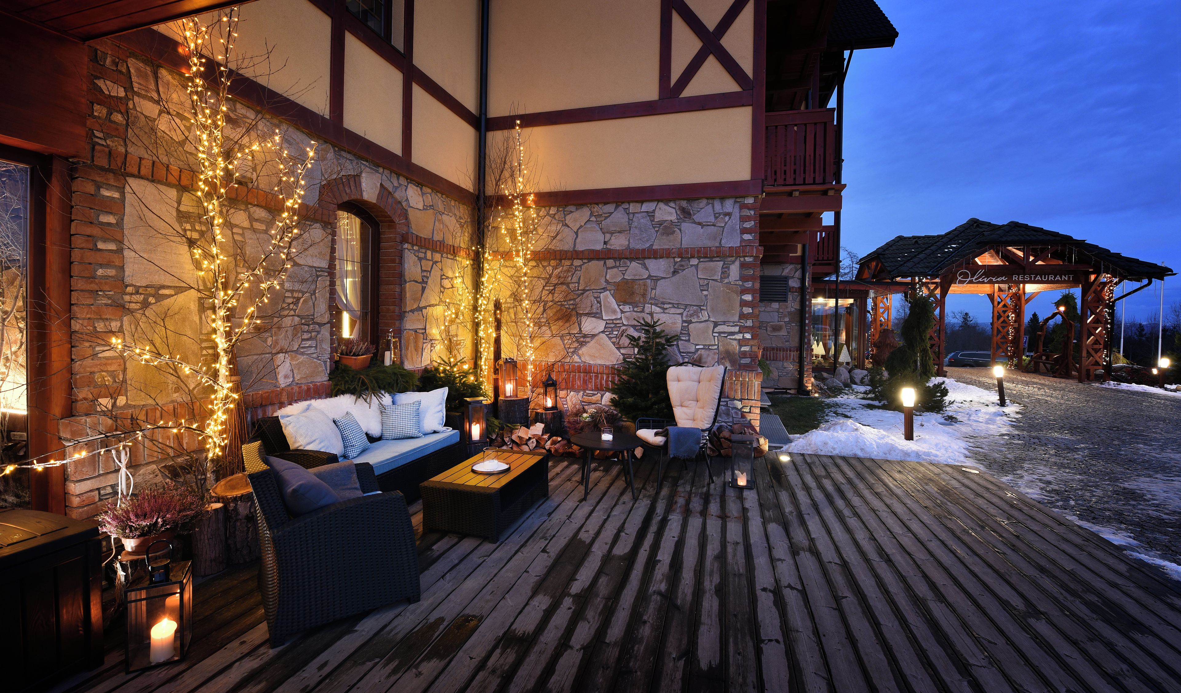 A cozy outdoor seating area with a stone wall, wooden deck, and string lights.