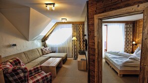 Una habitación acogedora con sofá, cama, piso de madera y techo inclinado.