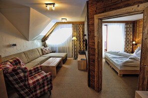 Una habitación acogedora con sofá, cama, piso de madera y techo inclinado.