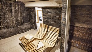 A room with a stone wall, a wooden bench, and a tiled floor.