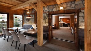 A cozy restaurant with wooden beams, stone walls, and a view of the outside.