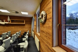 Un salón de conferencias con una pared de madera, un ventanal con vistas a terreno cubierto de nieve y varias sillas dispuestas para reuniones.