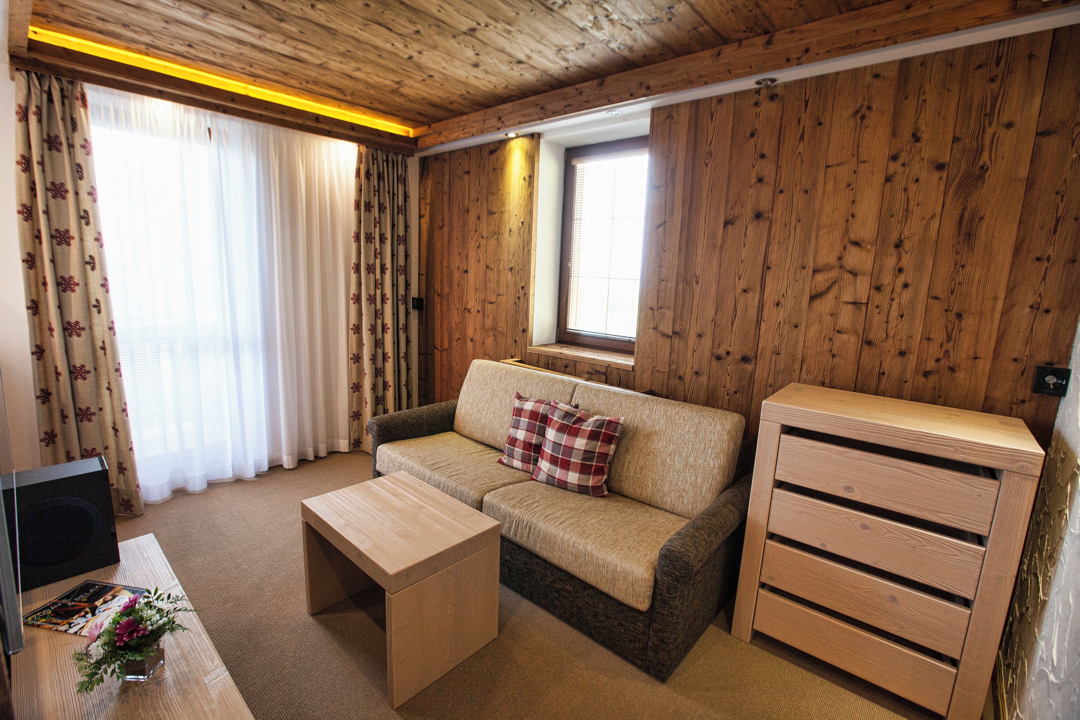 Una habitación acogedora con un sofá, una mesita de centro y un armario de madera.