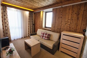 A cozy room with a sofa, a coffee table, and a wooden cabinet. - Aplend Kukucka Mountain Hotel & Residences (Vysoké Tatry)